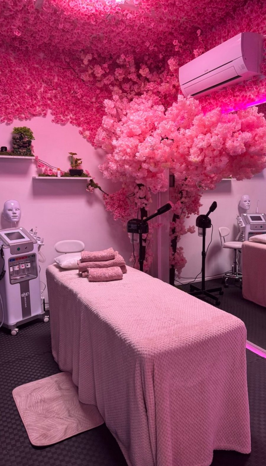La cabine des soins visage, sous un plafond de fleurs de cerisier, avec la table de soin et les appareils.