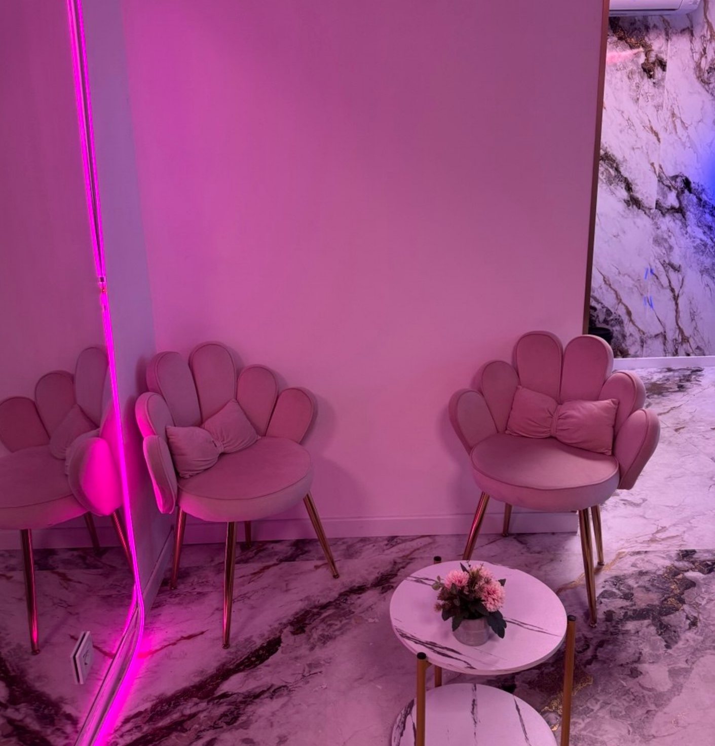 L’espace d’accueil : fauteuils roses en forme de coquillage, sol en marbre et petite table fleurie.